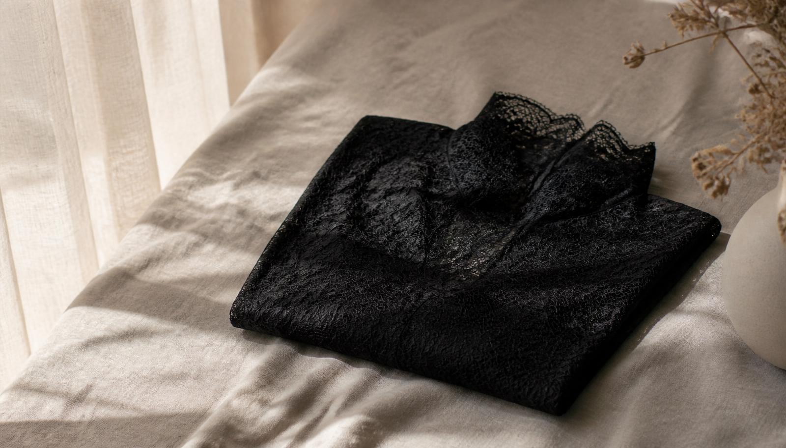 Femme portant un débardeur en dentelle noire avec un blazer écru